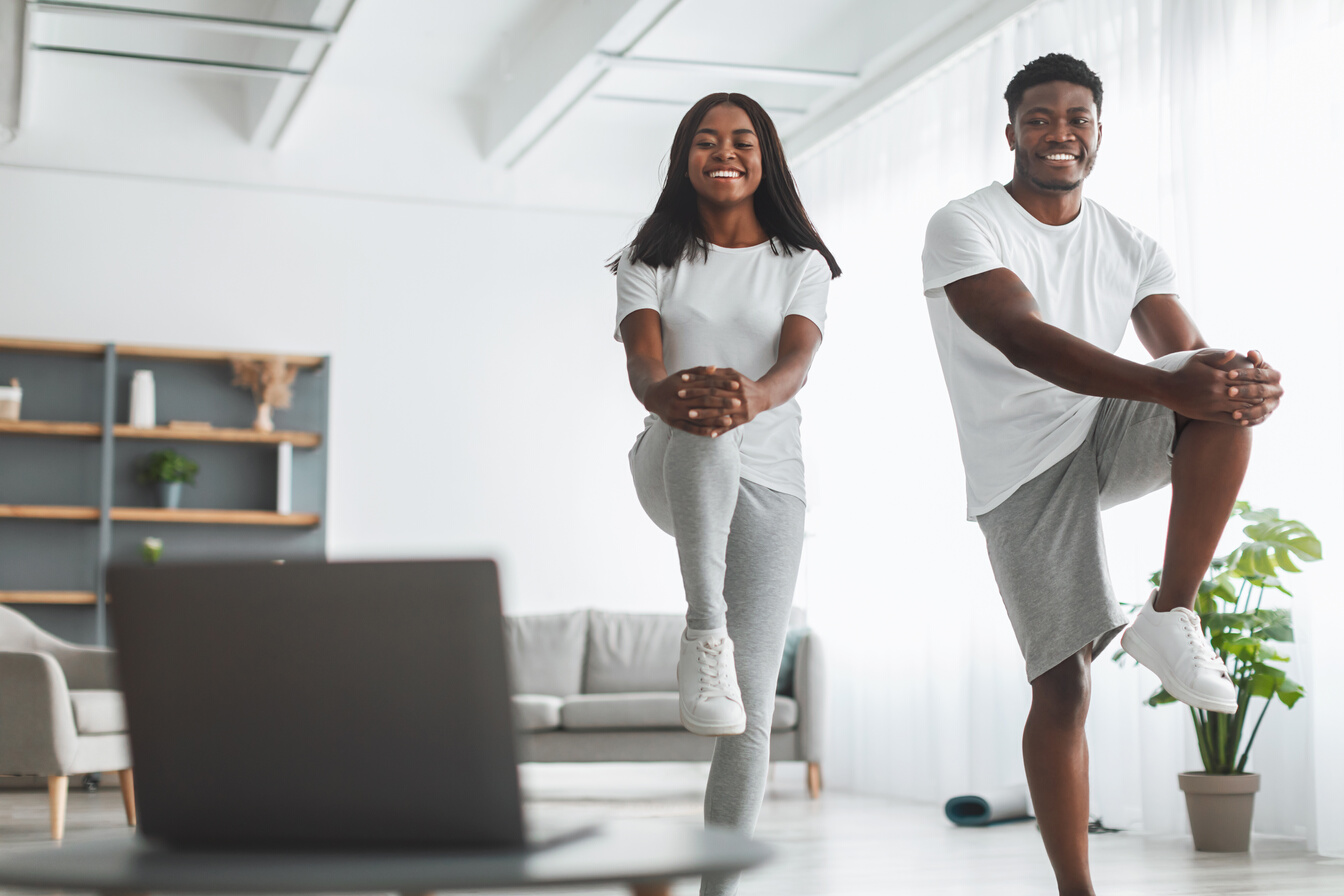Young Black Couple Doing High Knee Exercise with Pc